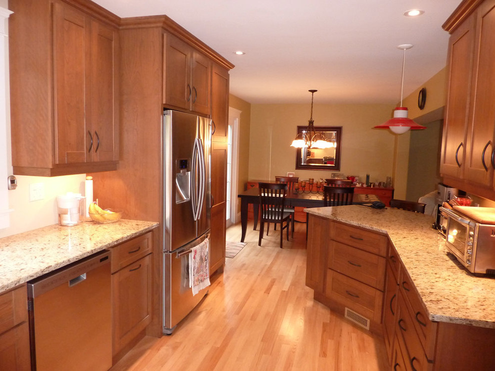Example of a mid-sized transitional galley light wood floor and beige floor open concept kitchen design with recessed-panel cabinets, medium tone wood cabinets, stainless steel appliances and a peninsula