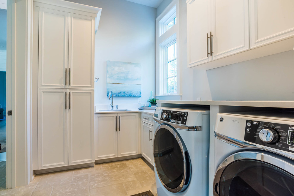 Expansive traditional l-shaped dedicated laundry room in Other with a drop-in sink, shaker cabinets, white cabinets, granite benchtops, grey walls, a side-by-side washer and dryer, beige floor and white benchtop.
