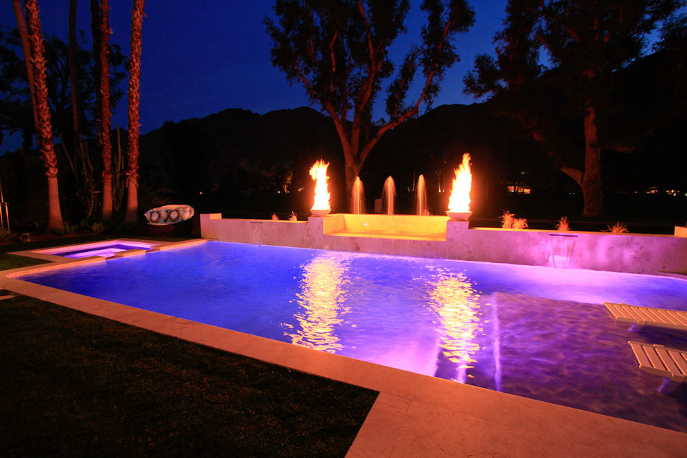 Photo of a mid-sized modern backyard rectangular natural pool in Los Angeles with a hot tub and natural stone pavers.