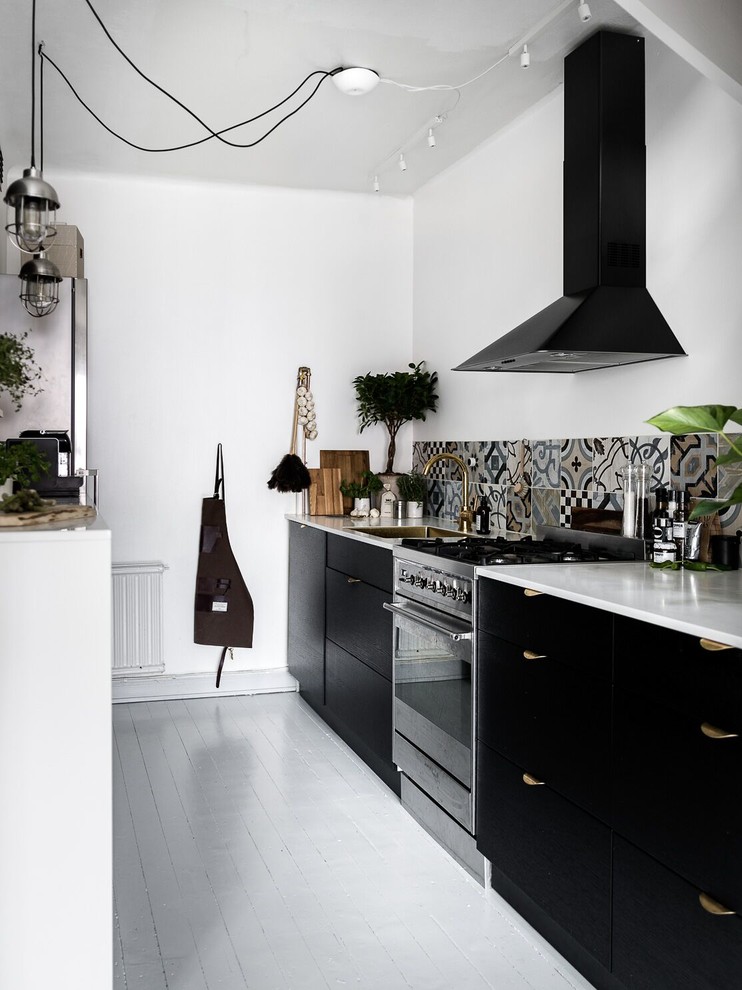 This is an example of a mid-sized scandinavian kitchen in Stockholm with an undermount sink, flat-panel cabinets, black cabinets, multi-coloured splashback, stainless steel appliances, painted wood floors and marble benchtops.