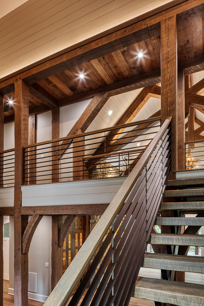 This is an example of a mid-sized arts and crafts wood floating staircase in Other with open risers, metal railing and planked wall panelling.