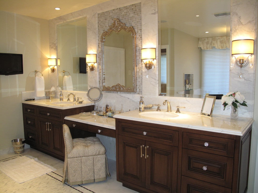 Large traditional master bathroom in Los Angeles with raised-panel cabinets, dark wood cabinets, gray tile, white tile, stone tile, beige walls, marble floors, an undermount sink, marble benchtops, a drop-in tub, a corner shower and a two-piece toilet.