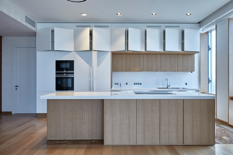 This is an example of a large contemporary single-wall eat-in kitchen in Moscow with a double-bowl sink, white cabinets, white splashback, laminate floors, with island, brown floor and white benchtop.