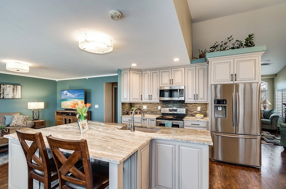 Eat-in kitchen - transitional galley eat-in kitchen idea in Denver with a double-bowl sink, raised-panel cabinets, gray cabinets, granite countertops, gray backsplash and an island