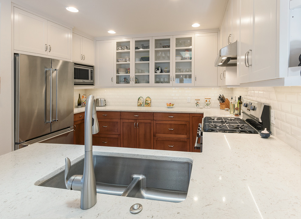Inspiration for a transitional light wood floor kitchen remodel with a double-bowl sink, shaker cabinets, quartz countertops, white backsplash, subway tile backsplash and stainless steel appliances