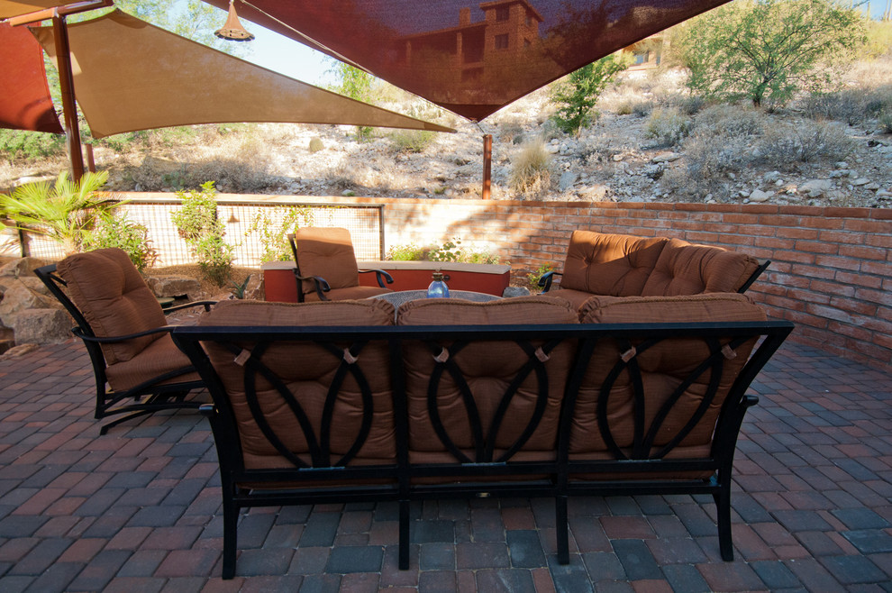 This is an example of a mid-sized backyard patio in Phoenix with brick pavers and an awning.
