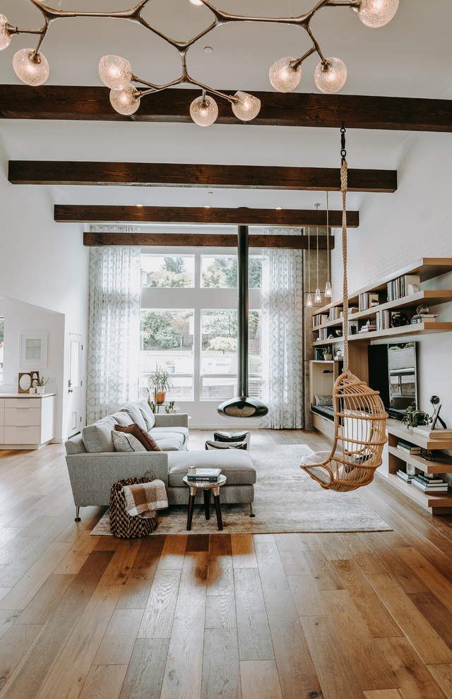 Inspiration for a contemporary family room in Seattle with white walls, medium hardwood floors, a hanging fireplace, a wall-mounted tv and brown floor.