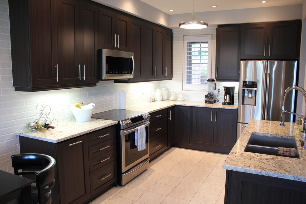 Mid-sized modern l-shaped open plan kitchen in Toronto with an undermount sink, shaker cabinets, dark wood cabinets, granite benchtops, white splashback, ceramic splashback, stainless steel appliances, ceramic floors and with island.