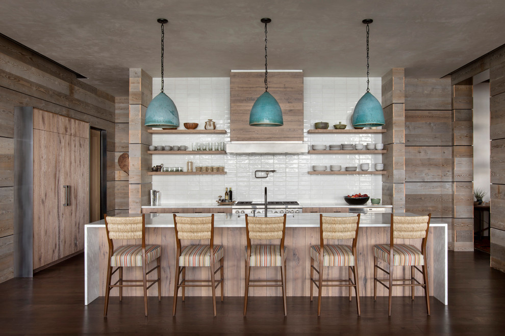 Inspiration for a large rustic galley brown floor and dark wood floor kitchen remodel with flat-panel cabinets, medium tone wood cabinets, marble countertops, white backsplash, ceramic backsplash, paneled appliances, an island, white countertops and a single-bowl sink