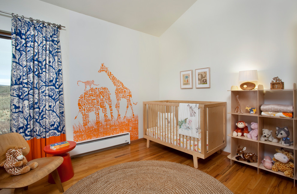 Cette image montre une chambre de bébé neutre traditionnelle de taille moyenne avec un mur blanc, un sol en bois brun, un sol marron, un plafond voûté et du papier peint.