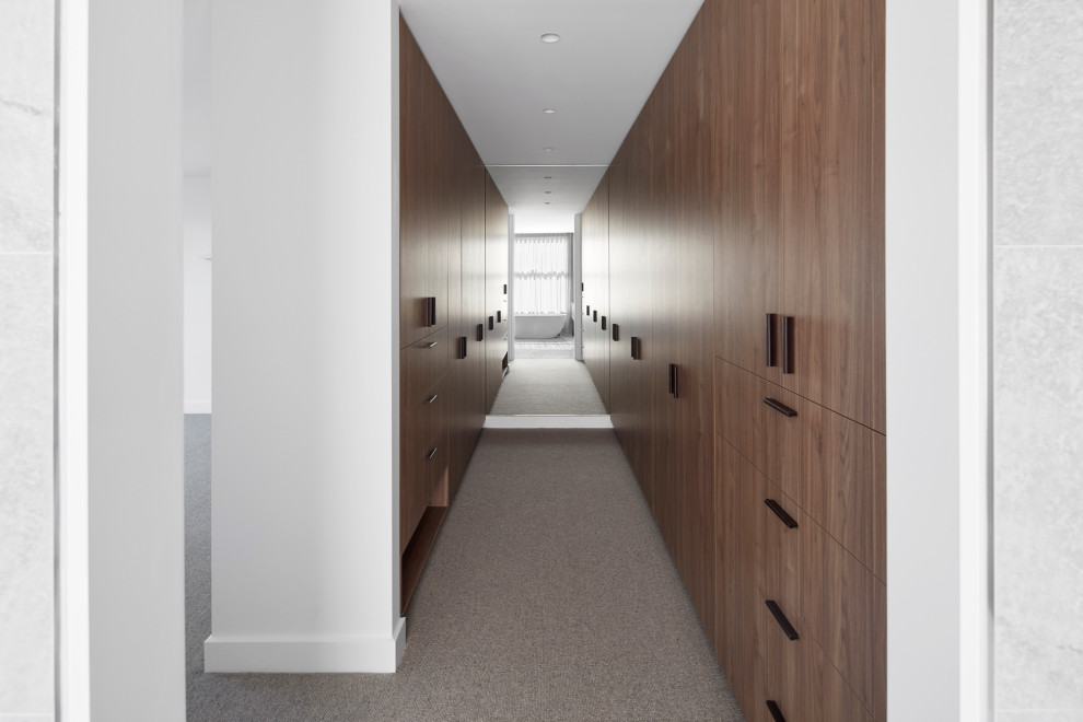 Large contemporary gender-neutral walk-in wardrobe in Melbourne with medium wood cabinets, carpet and grey floor.