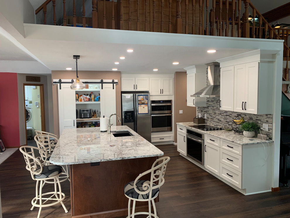 Inspiration for a mid-sized transitional l-shaped eat-in kitchen remodel with shaker cabinets, white cabinets, granite countertops, multicolored backsplash and an island