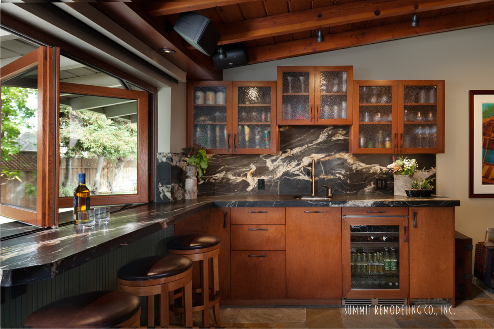 Inspiration for a large modern l-shaped seated home bar in San Francisco with an undermount sink, flat-panel cabinets, medium wood cabinets, granite benchtops, black splashback, stone slab splashback and slate floors.
