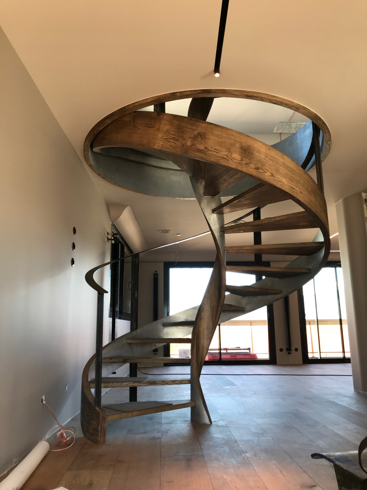 Photo of a large contemporary wood spiral staircase in Grenoble with wood railing.