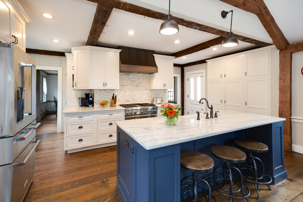 Mid-sized country l-shaped open plan kitchen in Providence with a farmhouse sink, beaded inset cabinets, white cabinets, quartzite benchtops, white splashback, brick splashback, stainless steel appliances, medium hardwood floors and with island.