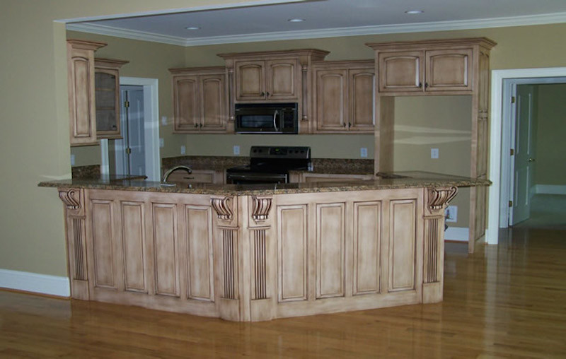 Large medium tone wood floor kitchen photo with recessed-panel cabinets, beige cabinets, granite countertops and black appliances