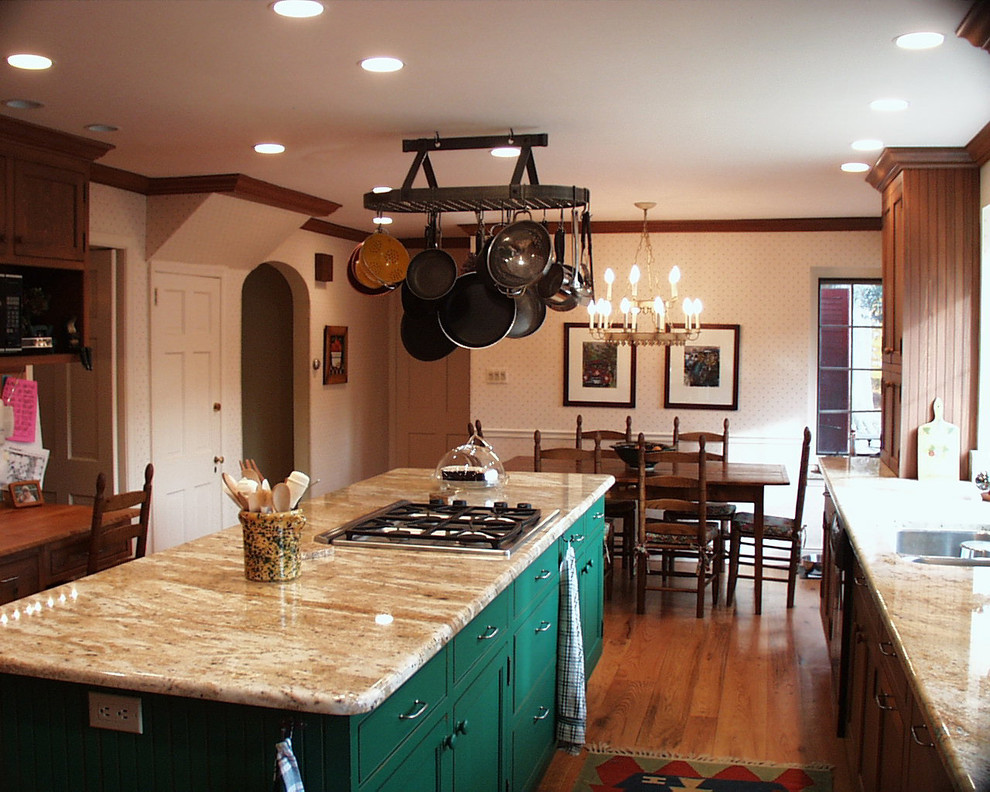 Photo of a mid-sized country galley eat-in kitchen in Philadelphia with a double-bowl sink, recessed-panel cabinets, medium wood cabinets, granite benchtops, beige splashback, stone slab splashback, black appliances, medium hardwood floors, with island and brown floor.