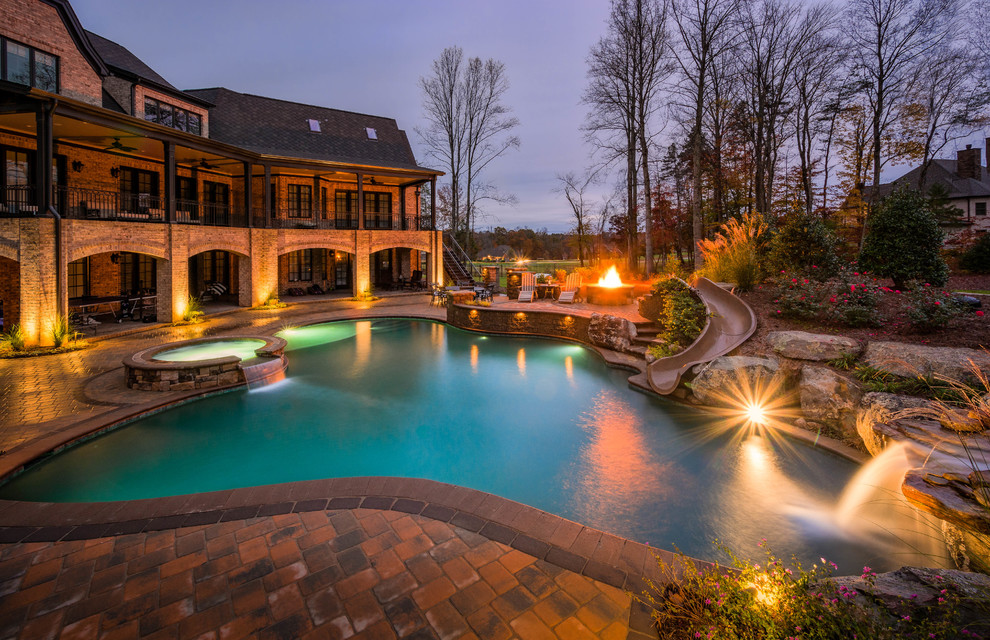 Mid-sized transitional backyard custom-shaped pool in Charlotte with a hot tub and brick pavers.
