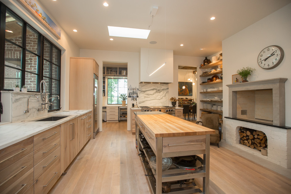 Inspiration for a transitional l-shaped kitchen in Other with an undermount sink, flat-panel cabinets, light wood cabinets, wood benchtops, window splashback, stainless steel appliances, light hardwood floors, with island, beige floor and white benchtop.