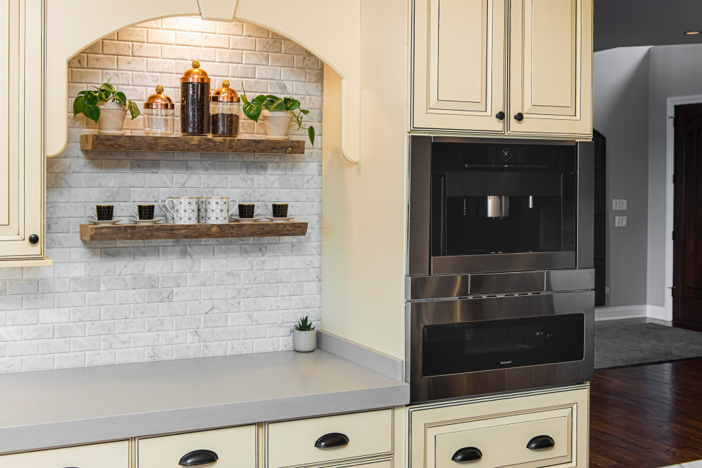 Example of an eclectic dark wood floor and black floor enclosed kitchen design in Indianapolis with granite countertops, subway tile backsplash, stainless steel appliances, gray countertops, raised-panel cabinets, gray backsplash and yellow cabinets