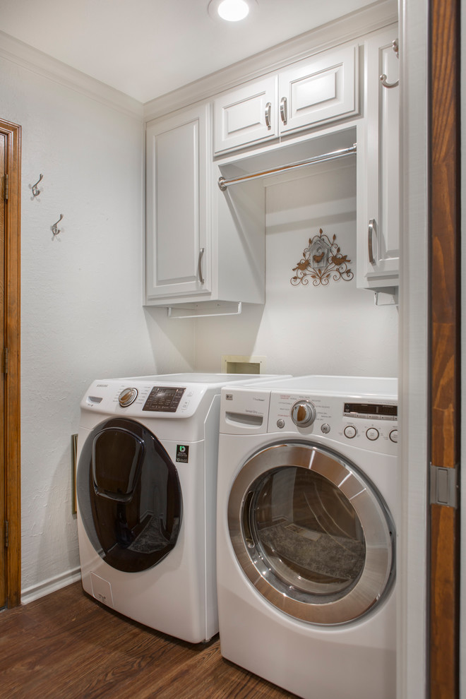This is an example of a large transitional laundry room in Other with a farmhouse sink, raised-panel cabinets, grey cabinets, quartzite benchtops, beige splashback, subway tile splashback, vinyl floors, brown floor and white benchtop.