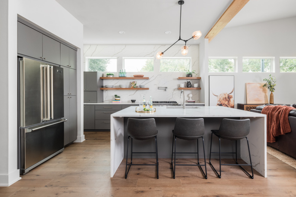 Small contemporary galley kitchen/diner in Austin with a single-bowl sink, flat-panel cabinets, grey cabinets, engineered stone countertops, white splashback, engineered quartz splashback, stainless steel appliances, medium hardwood flooring, an island, brown floors, white worktops and exposed beams.