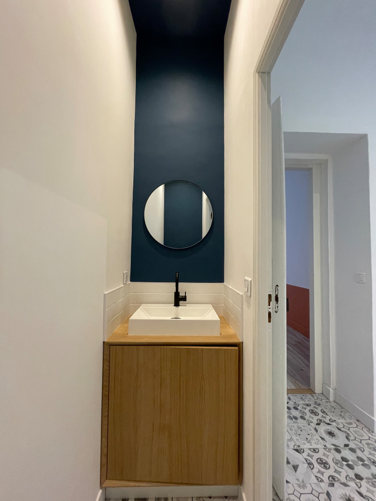 Photo of a medium sized modern cloakroom in Other with a one-piece toilet, white tiles, metro tiles, blue walls, cement flooring, a console sink, wooden worktops and grey floors.