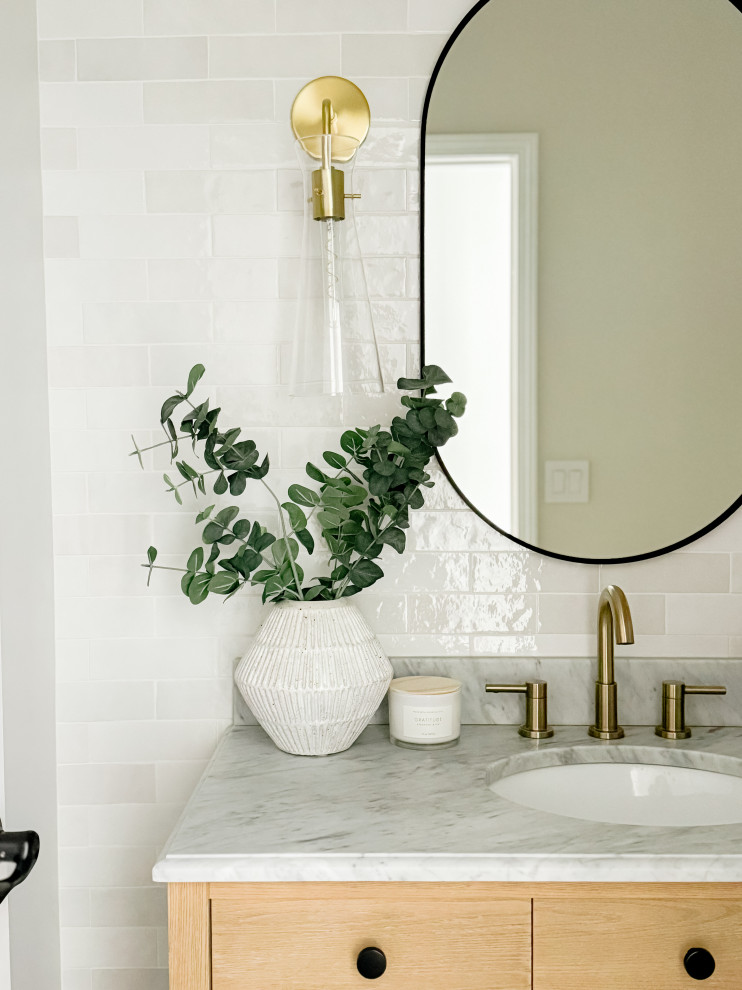 Small contemporary powder room in Detroit with furniture-like cabinets, light wood cabinets, a two-piece toilet, white tile, ceramic tile, grey walls, porcelain floors, an undermount sink, marble benchtops, grey floor, grey benchtops and a freestanding vanity.