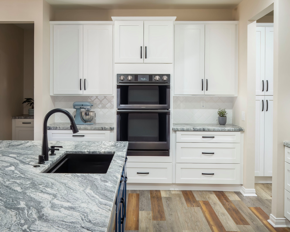 Klassisk inredning av ett stort grå grått kök, med en enkel diskho, skåp i shakerstil, blå skåp, granitbänkskiva, vitt stänkskydd, stänkskydd i keramik, svarta vitvaror, laminatgolv, en köksö och blått golv