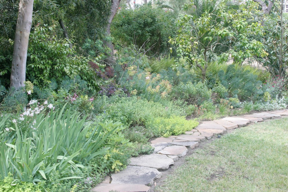 Large mediterranean backyard full sun garden in San Diego with a vegetable garden and natural stone pavers for summer.