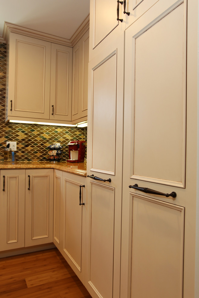 Photo of a mid-sized traditional u-shaped eat-in kitchen in Los Angeles with an undermount sink, recessed-panel cabinets, beige cabinets, granite benchtops, multi-coloured splashback, glass tile splashback, stainless steel appliances, bamboo floors, no island and beige floor.
