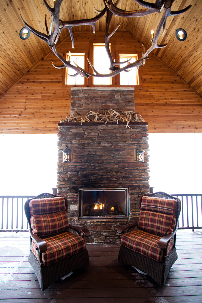 Inspiration for a large rustic backyard deck remodel with a fire pit and a roof extension