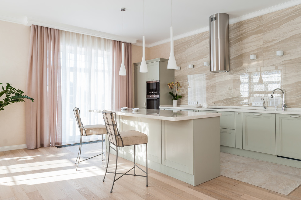 This is an example of a transitional single-wall kitchen in Other with recessed-panel cabinets, green cabinets, beige splashback, stainless steel appliances, with island, beige floor and white benchtop.