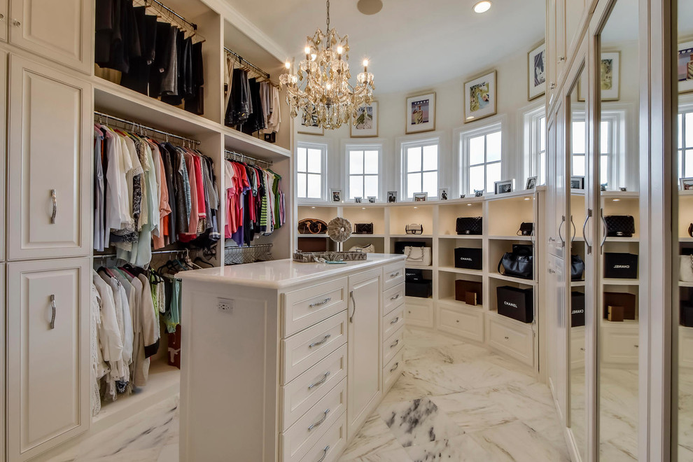 This is an example of a mediterranean women's dressing room in Austin with white cabinets and marble floors.