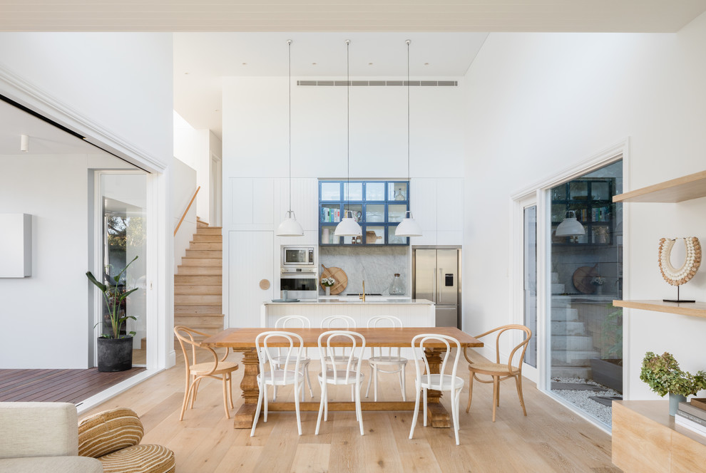Beach style kitchen/dining combo in Sydney with white walls, light hardwood floors and beige floor.