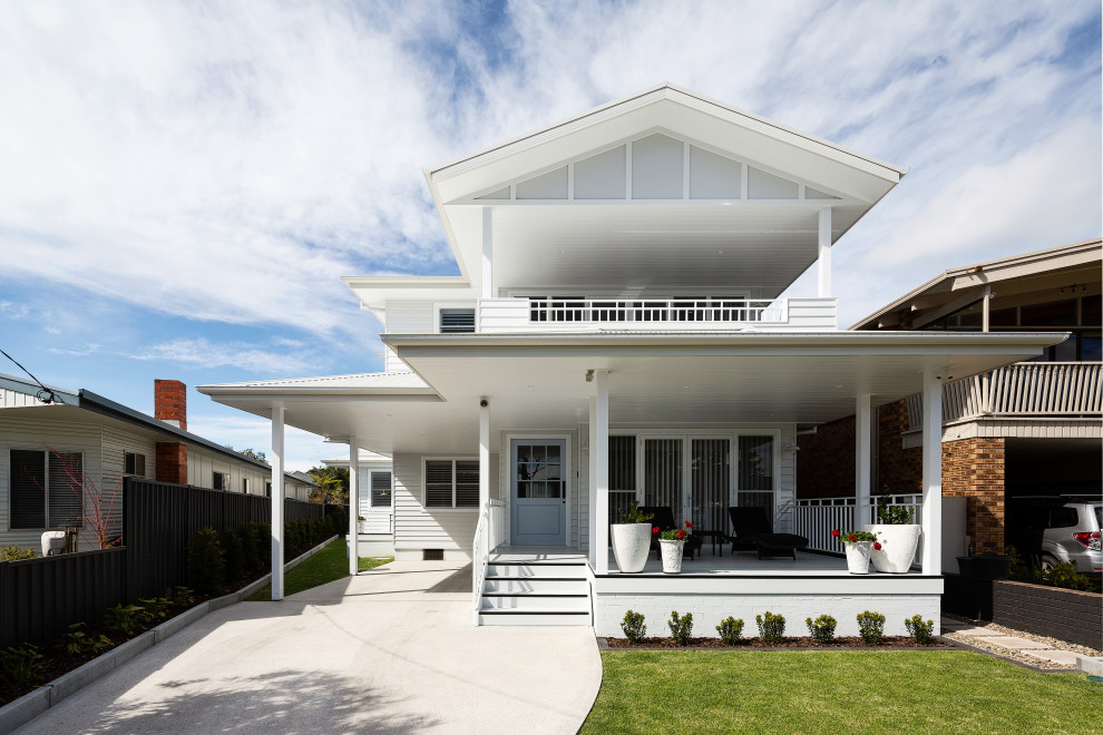 Large and white coastal two floor detached house in Sydney with concrete fibreboard cladding, a pitched roof, a metal roof, a white roof and board and batten cladding.