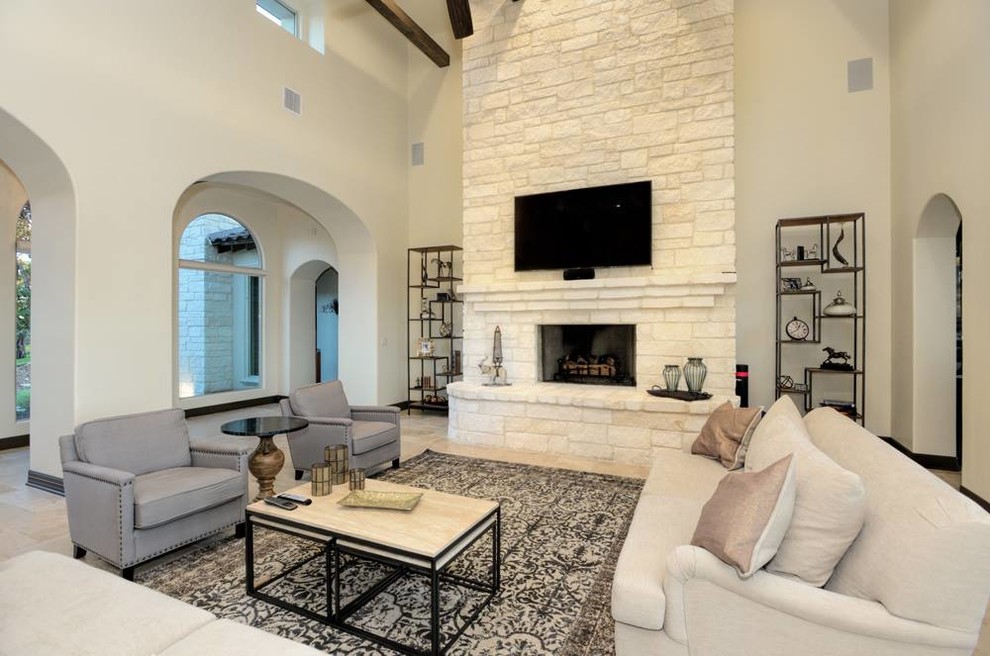 Large mediterranean open concept family room in Austin with beige walls, travertine floors, a standard fireplace, a stone fireplace surround and a wall-mounted tv.