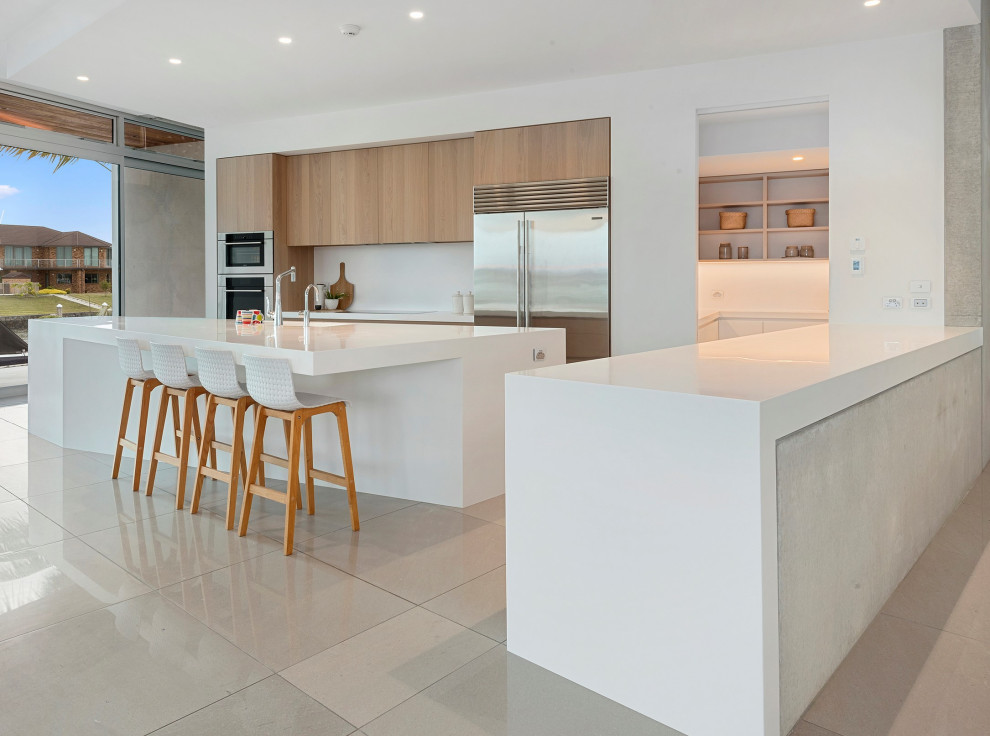 Large urban l-shaped porcelain tile and beige floor eat-in kitchen photo in Other with solid surface countertops, white backsplash, stainless steel appliances, an island and white countertops