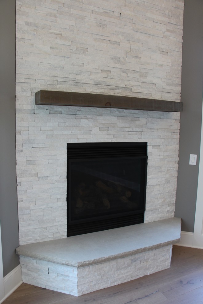Photo of a mid-sized modern formal enclosed living room in Cleveland with grey walls, medium hardwood floors, a standard fireplace, a stone fireplace surround and no tv.