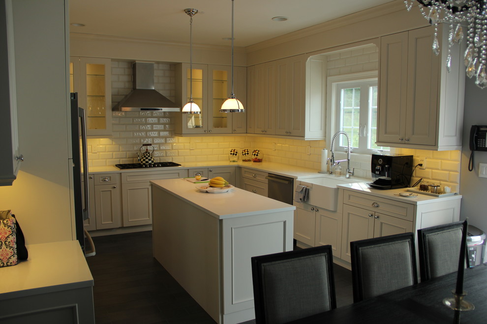 This is an example of a mid-sized contemporary u-shaped eat-in kitchen in New York with a farmhouse sink, recessed-panel cabinets, white cabinets, white splashback, subway tile splashback, panelled appliances, dark hardwood floors and with island.