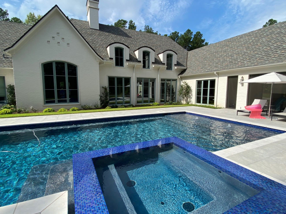 Esempio di una grande piscina naturale chic rettangolare dietro casa con una vasca idromassaggio e pavimentazioni in pietra naturale