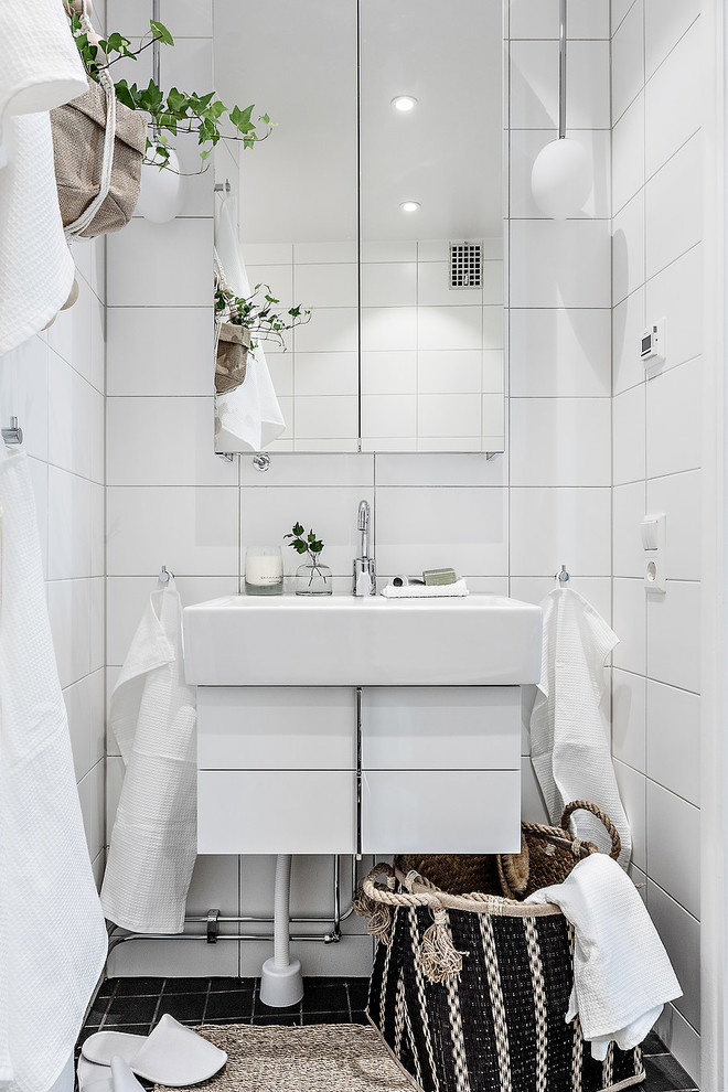 Inspiration for a small scandinavian bathroom in Stockholm with flat-panel cabinets, white cabinets, white tile, white walls and black floor.