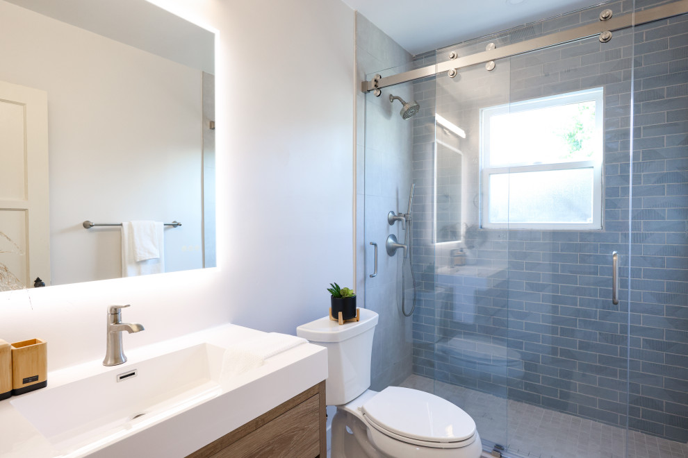 Пример оригинального дизайна: маленькая детская ванная комната в стиле модернизм с плоскими фасадами, светлыми деревянными фасадами, душем в нише, раздельным унитазом, синей плиткой, керамогранитной плиткой, белыми стенами, полом из керамогранита, врезной раковиной, столешницей из искусственного кварца, серым полом, белой столешницей, нишей, тумбой под одну раковину и подвесной тумбой для на участке и в саду