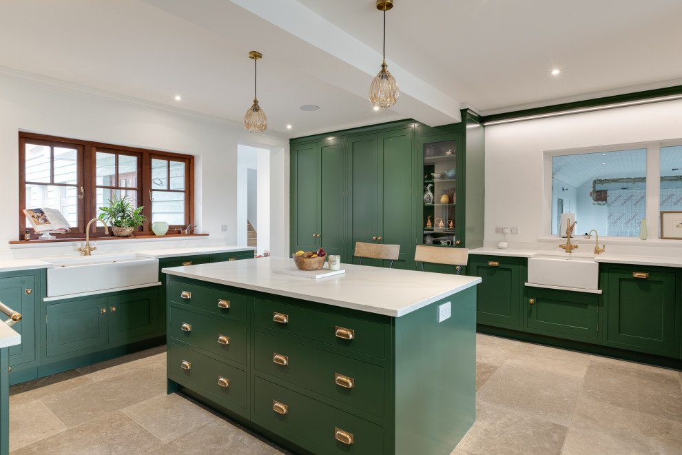 This is an example of an expansive traditional galley open plan kitchen in Hertfordshire with a belfast sink, recessed-panel cabinets, medium wood cabinets, quartz worktops, white splashback, engineered quartz splashback, black appliances, limestone flooring, an island, beige floors, white worktops, a drop ceiling and a chimney breast.