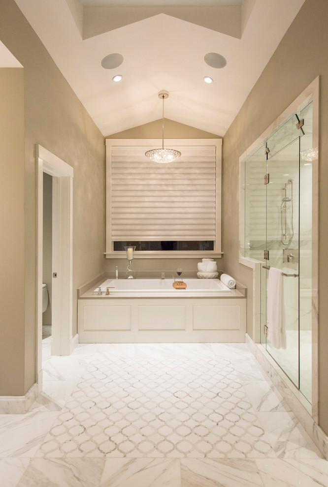 Example of a huge transitional master white tile and ceramic tile marble floor and white floor drop-in bathtub design in Denver with shaker cabinets, white cabinets, a two-piece toilet, beige walls, an undermount sink, marble countertops and a hinged shower door