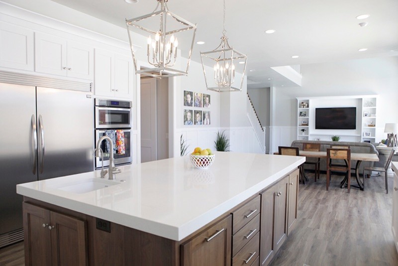 Mid-sized u-shaped medium tone wood floor and brown floor open concept kitchen photo with a drop-in sink, shaker cabinets, white cabinets, marble countertops, stainless steel appliances and an island
