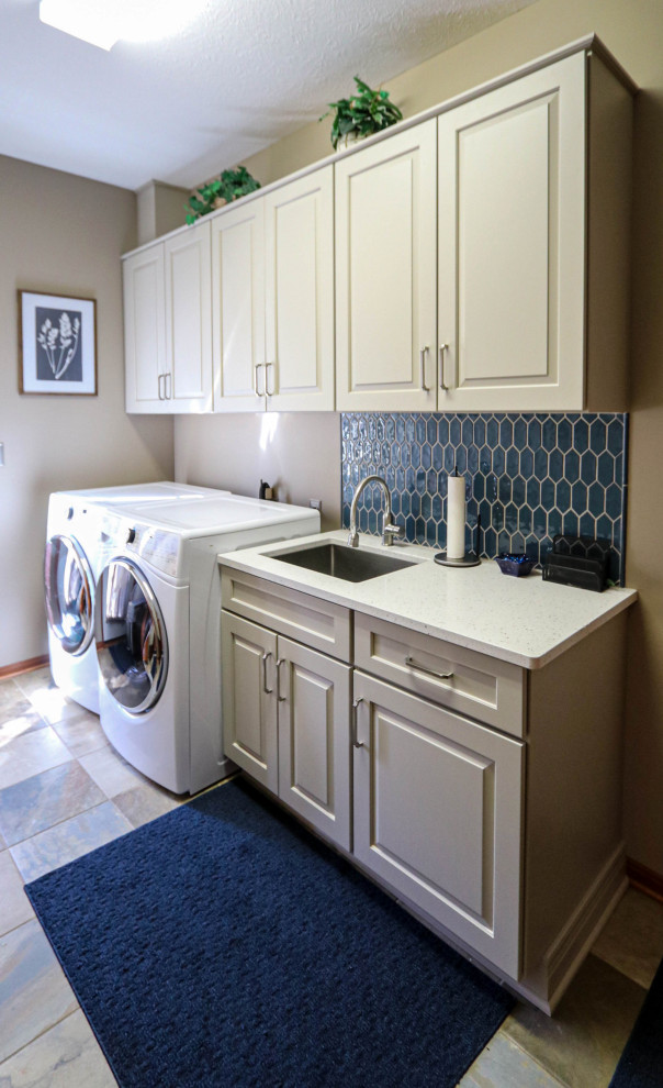 Foto på en liten vintage vita linjär tvättstuga enbart för tvätt, med en undermonterad diskho, luckor med upphöjd panel, vita skåp, bänkskiva i kvarts, blått stänkskydd, stänkskydd i cementkakel, grå väggar och en tvättmaskin och torktumlare bredvid varandra