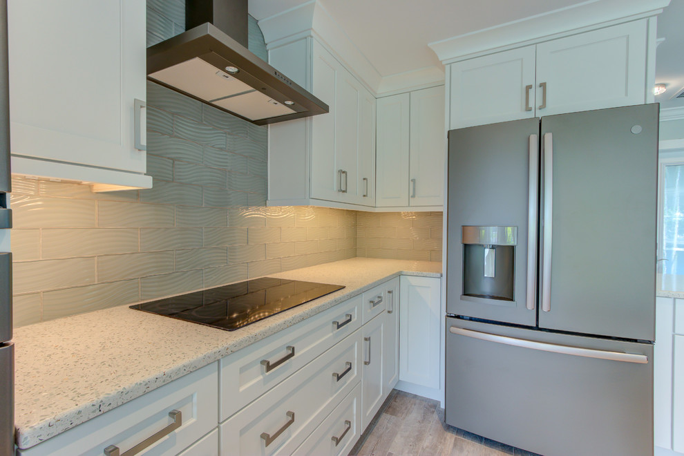 This is an example of a large transitional l-shaped open plan kitchen in Other with shaker cabinets, white cabinets, recycled glass benchtops, blue splashback, glass tile splashback, stainless steel appliances, with island, white benchtop, an undermount sink, ceramic floors and grey floor.