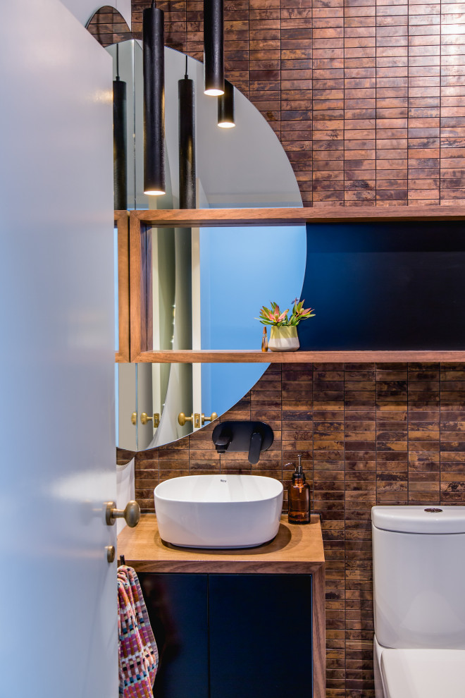 Ispirazione per un bagno di servizio minimal con ante lisce, ante nere, piastrelle marroni, lavabo a bacinella, top in legno e top marrone