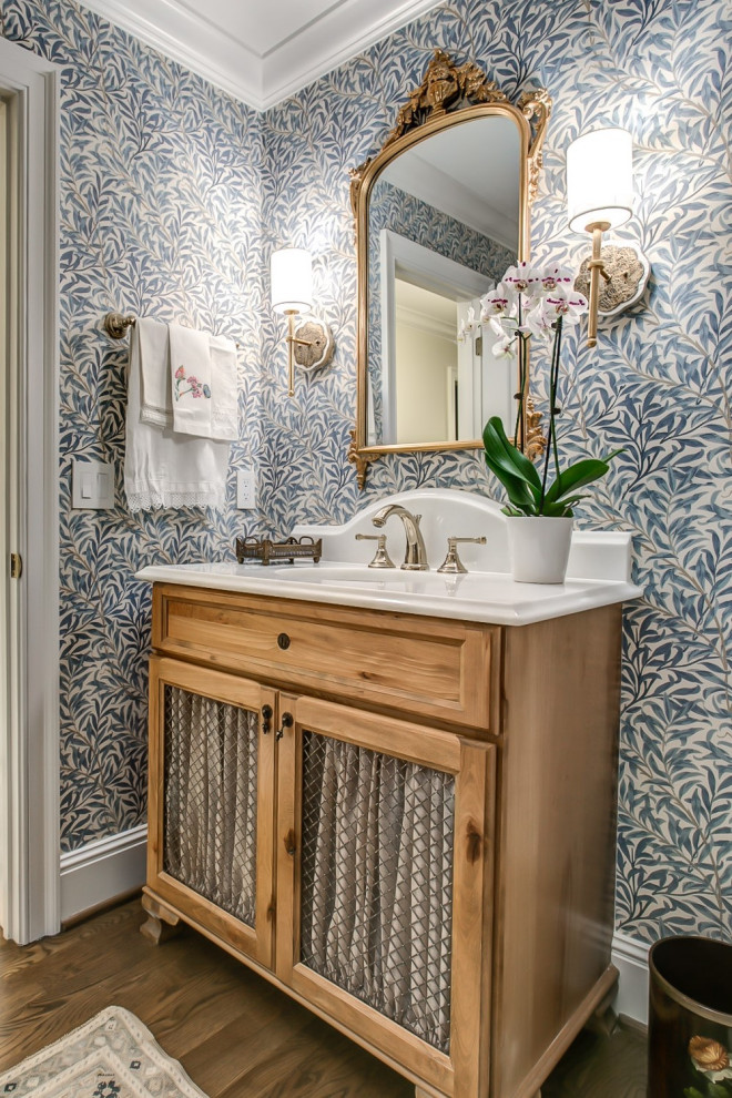 Cette photo montre une salle de bain en bois clair avec un placard sans porte, un mur bleu, un sol en bois brun, un sol marron, meuble simple vasque, meuble-lavabo sur pied et du papier peint.